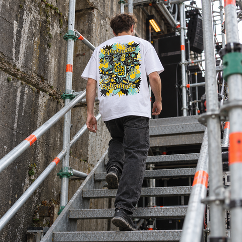 Man walking up metal venue stairs wearing the white BXL T-shirt with yellow and mint Electronic Subculture back artwork